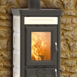 Sofia Evo-brændeovn med beige Maiolica-beklædning, ilden brænder bag glasruden foran en stenmur.