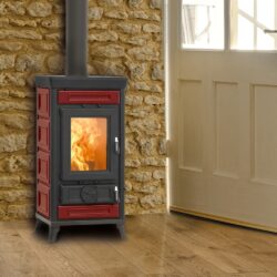 Rød Sofia Evo Maiolica-brændeovn foran en stenmur med synlig ild gennem glasdøren.