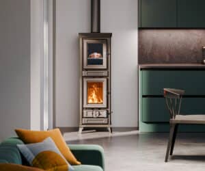 Moderne brændeovn i et stilfuldt køkken-alrum med store glasruder og metalaccenter, der brænder synligt.