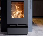 Modern wood-burning stove with visible flames, focusing on the rectangular glass front. Elegant, dark design.