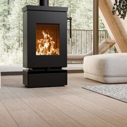 Modern black stove with blazing fire, in a cozy room with wooden floor and large windows.