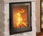 Kaminofen mit weißer Kachelverkleidung und brennendem Feuer hinter einer großen Sichtscheibe. Elegantes Design im Innenraum.