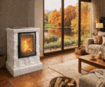 Weißer Kaminofen mit brennendem Feuer in einem gemütlichen Wohnzimmer. Große Fenster zeigen eine herbstliche Landschaft mit See und bunten Bäumen.